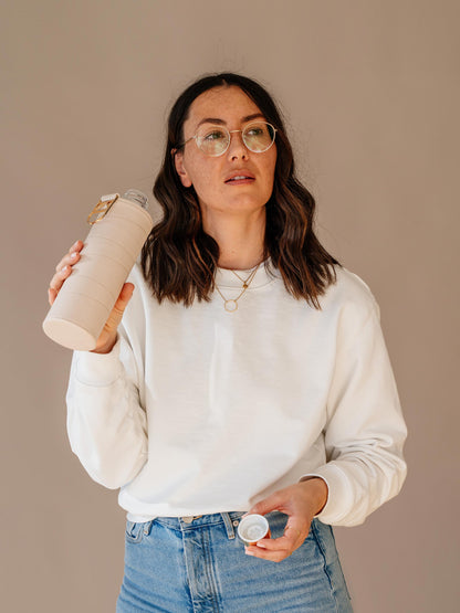 Girl drinking from glass bottle with beige faux leather cover