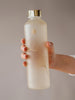 Holding Mismatch Ginkgo glass water bottle with matte finish and gold lid