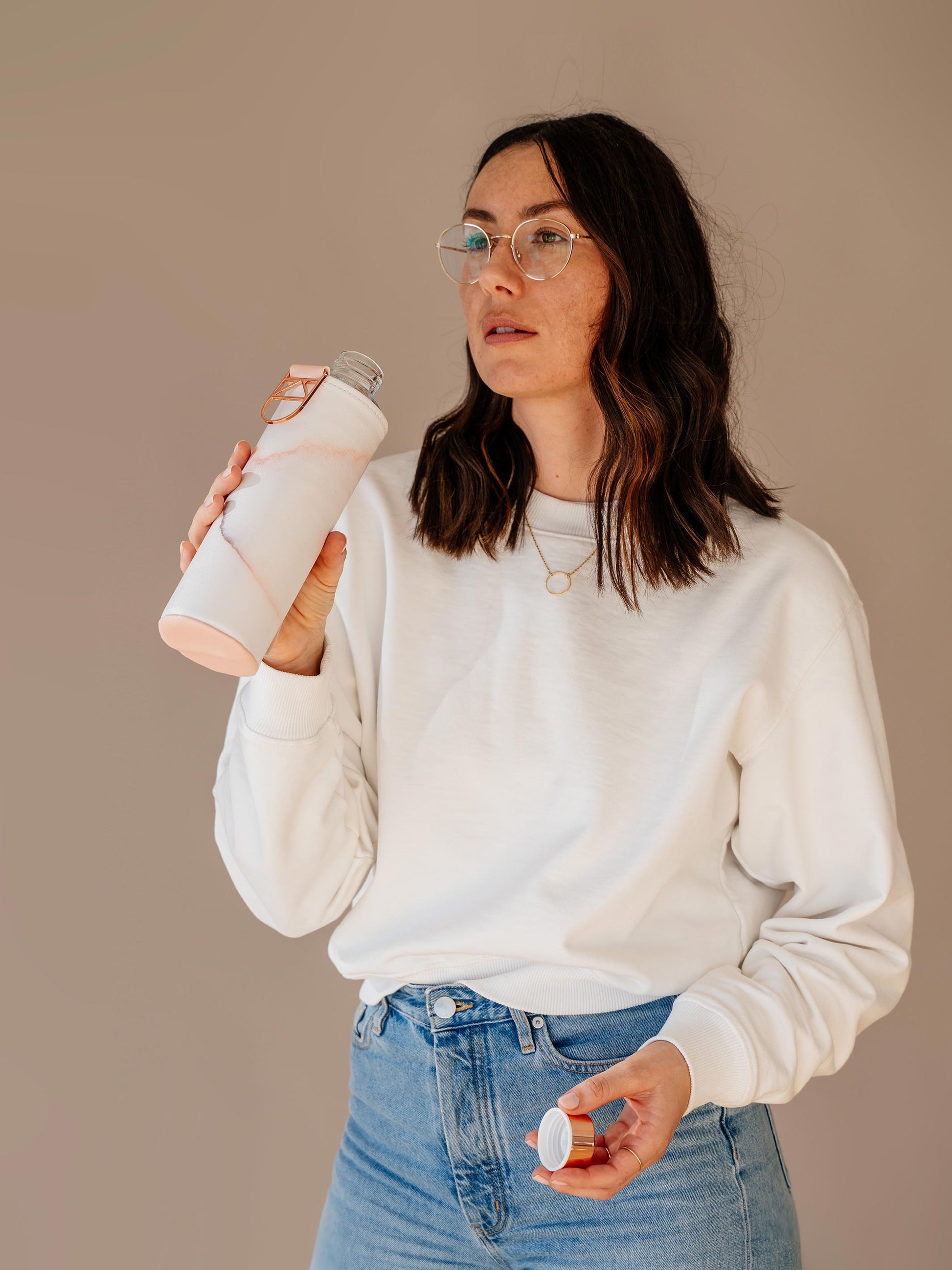 Girl drinking from glass bottle with marble faux leather cover