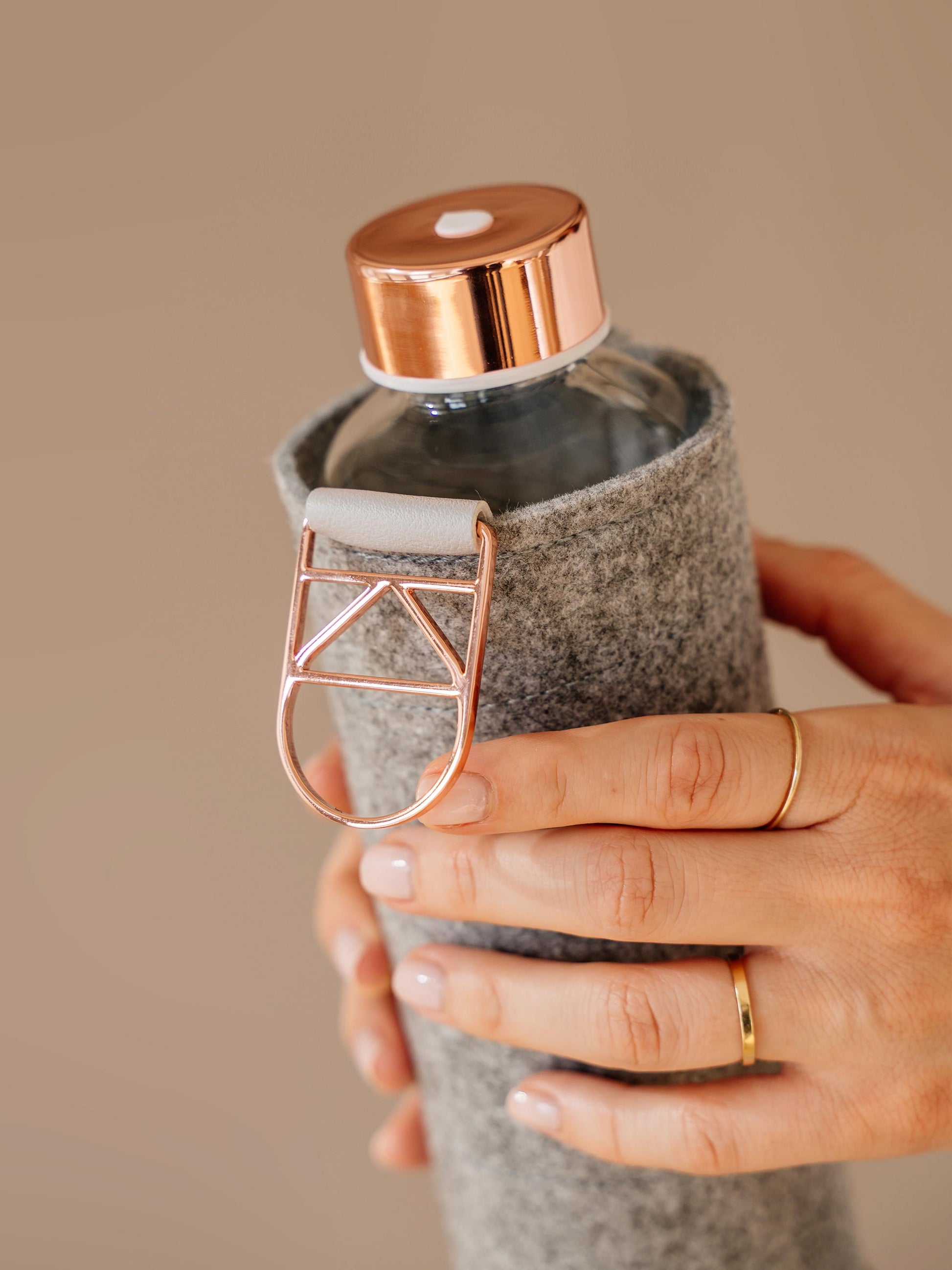 Holding Mismatch Rose Gold glass bottle with grey felt cover 