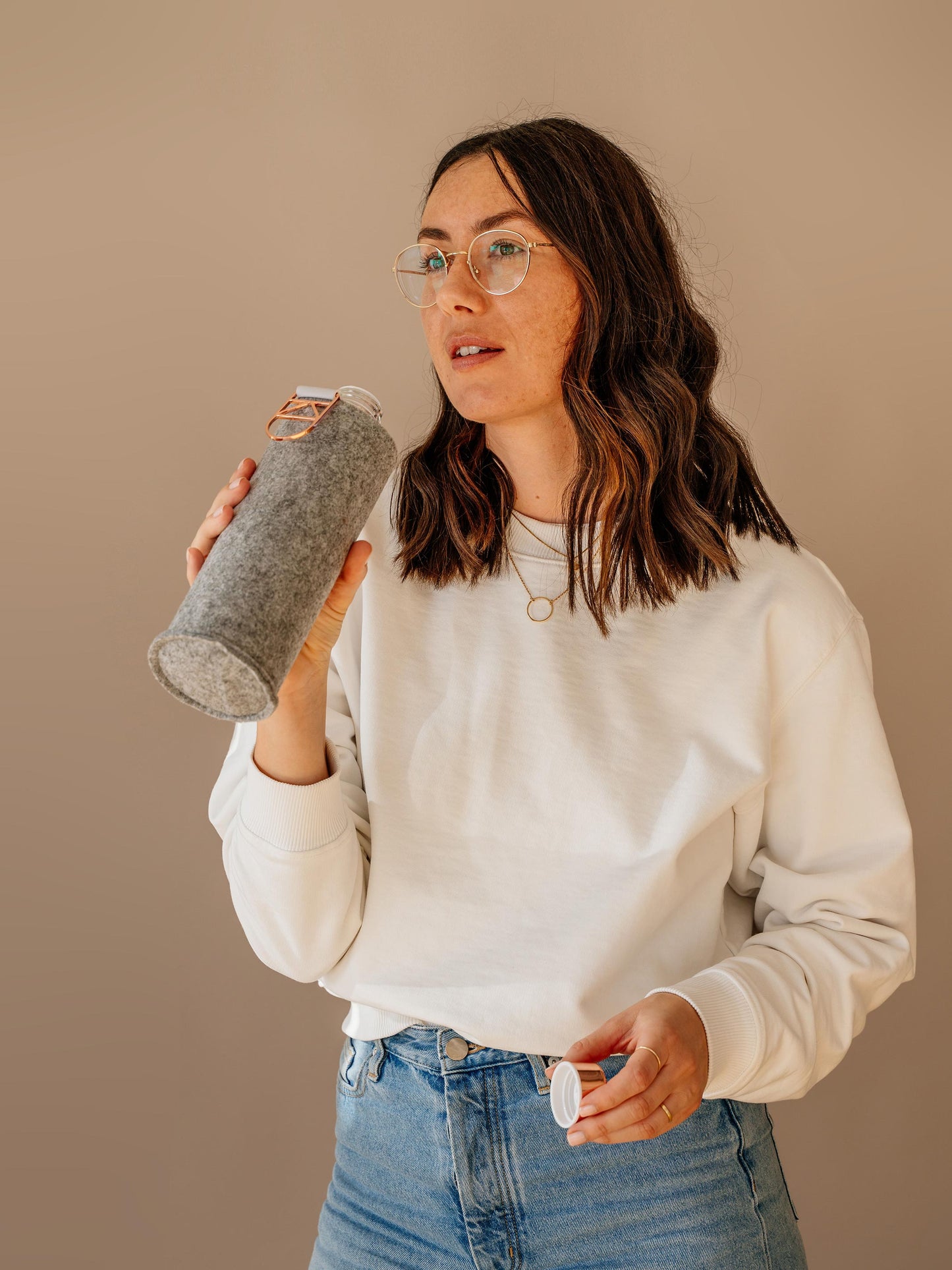 Girl drinking from Mismatch Rose Gold glass bottle with grey felt cover