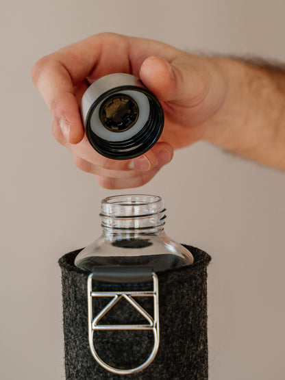 Close up of holding silver lid of Mismatch Silver glass water bottle