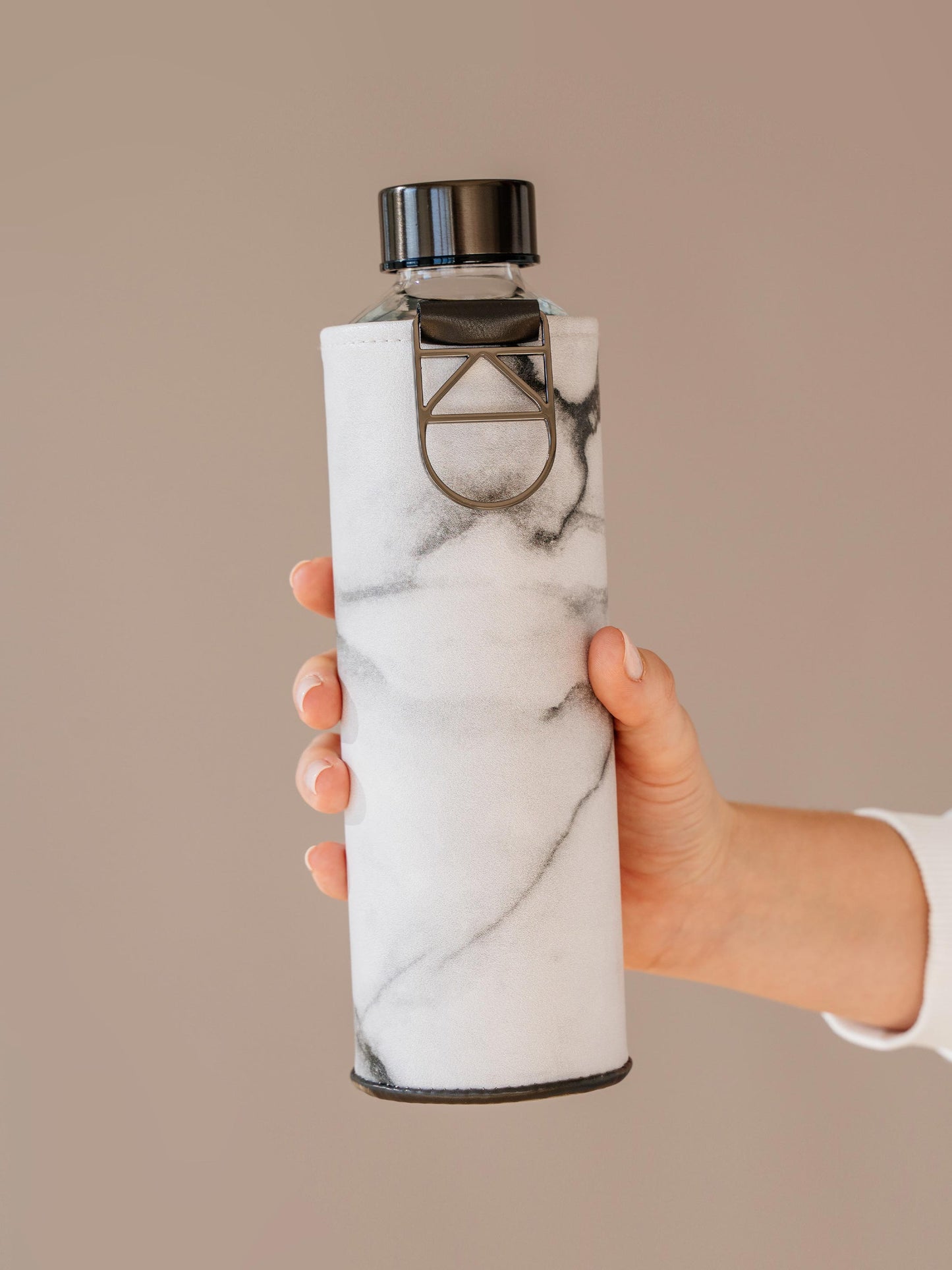 Holding Mismatch Stone glass bottle with marble faux leather cover by EQUA