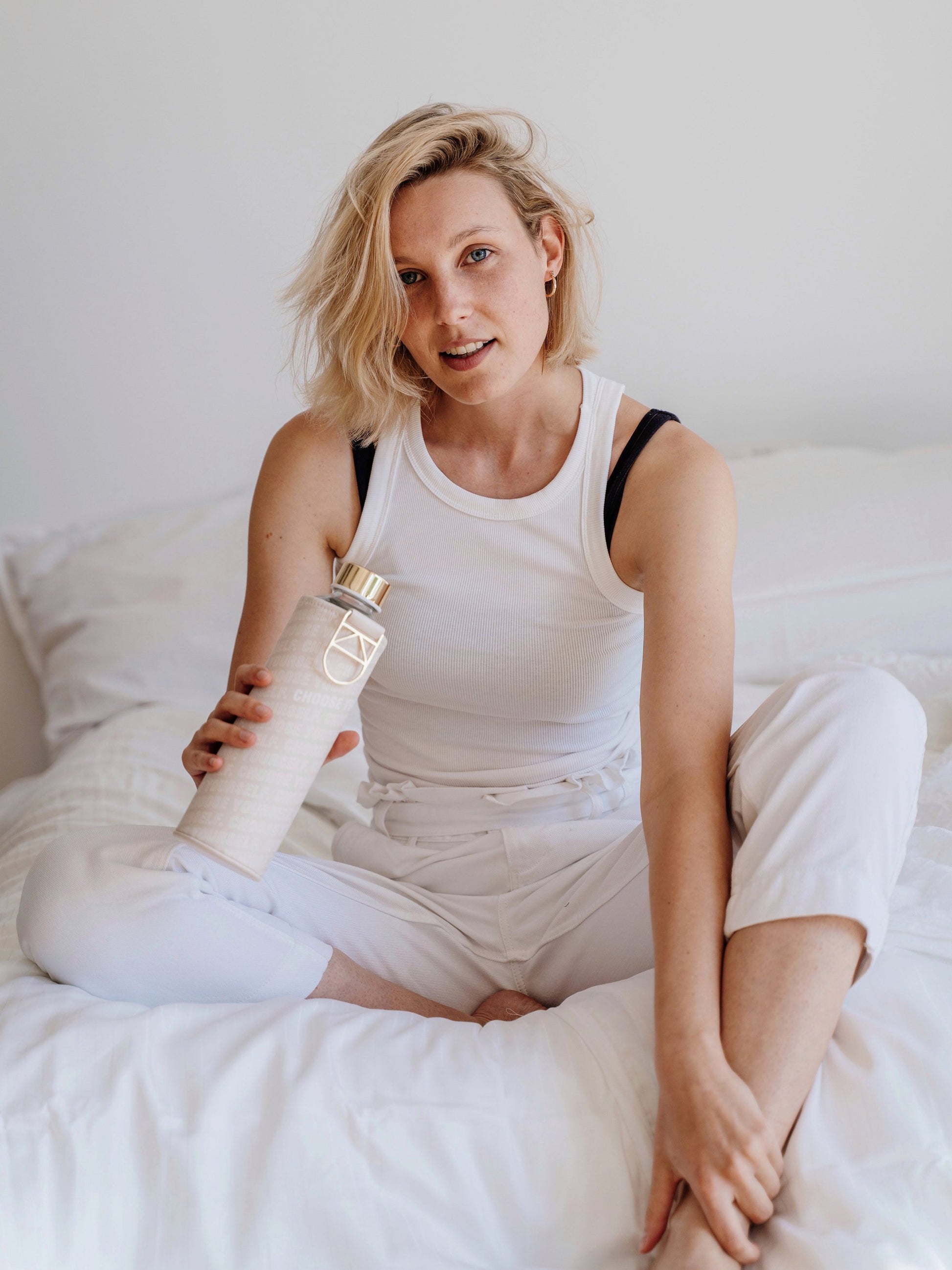 Girl sitting on the bed and holding Mismatch Choose Yourself glass water bottle