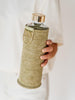 EQUA Pistachio reusable glass water bottle with green felt cover and golden metal holder and lid