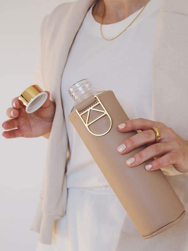 Gold lid and details of glass water bottle with beige colour cover - Sienna by EQUA