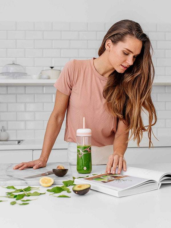 EQUA BPA FREE FLOW 2 in 1 water bottle, Beat, bootle is shown with the straw and smoothie, young woman is browsing smoothie recipes, graphic motif, peach color